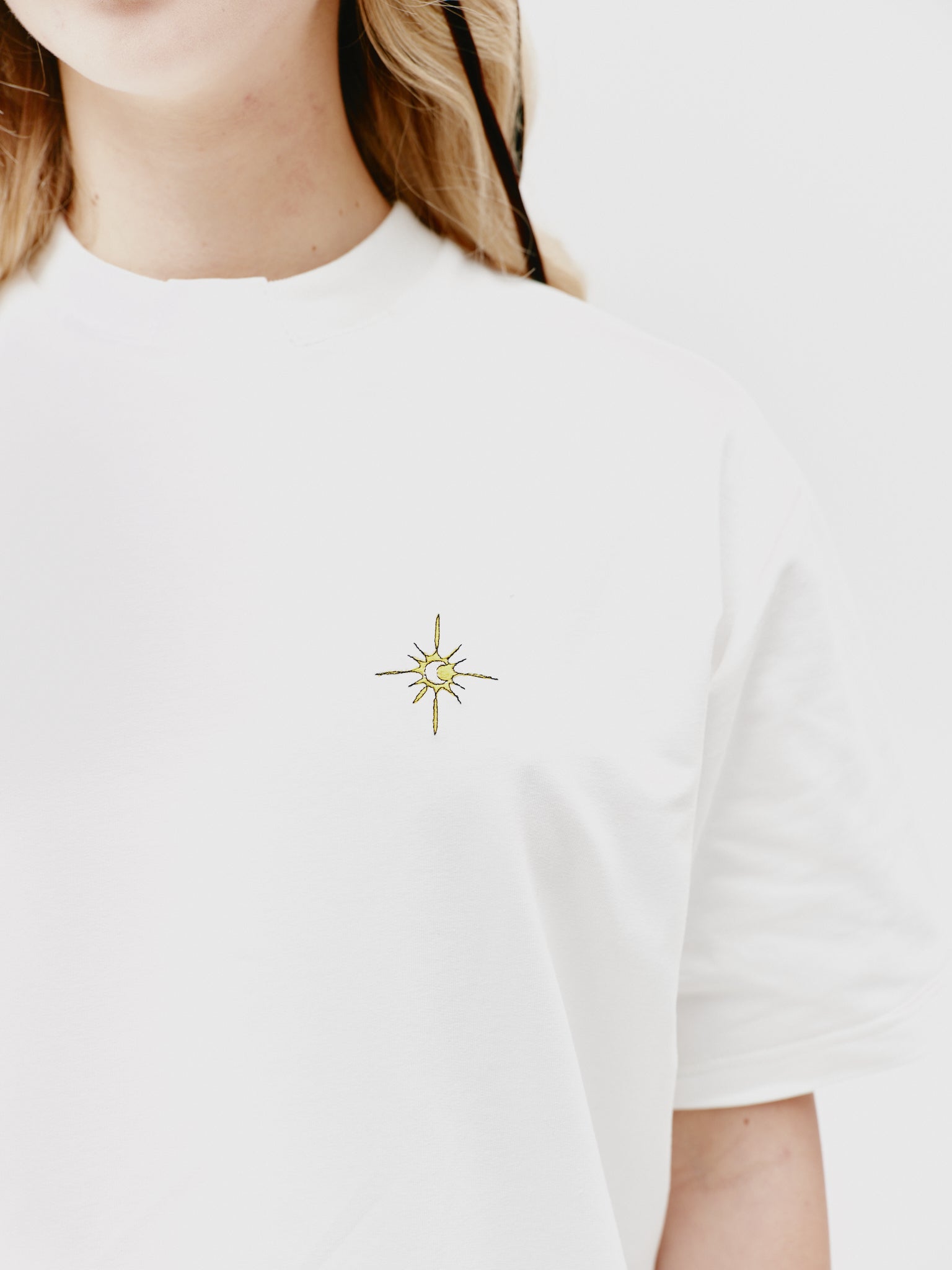 Close-up of a white unisex cotton t-shirt featuring a stand-up collar and delicate embroidery, emphasizing its elegant yet casual style