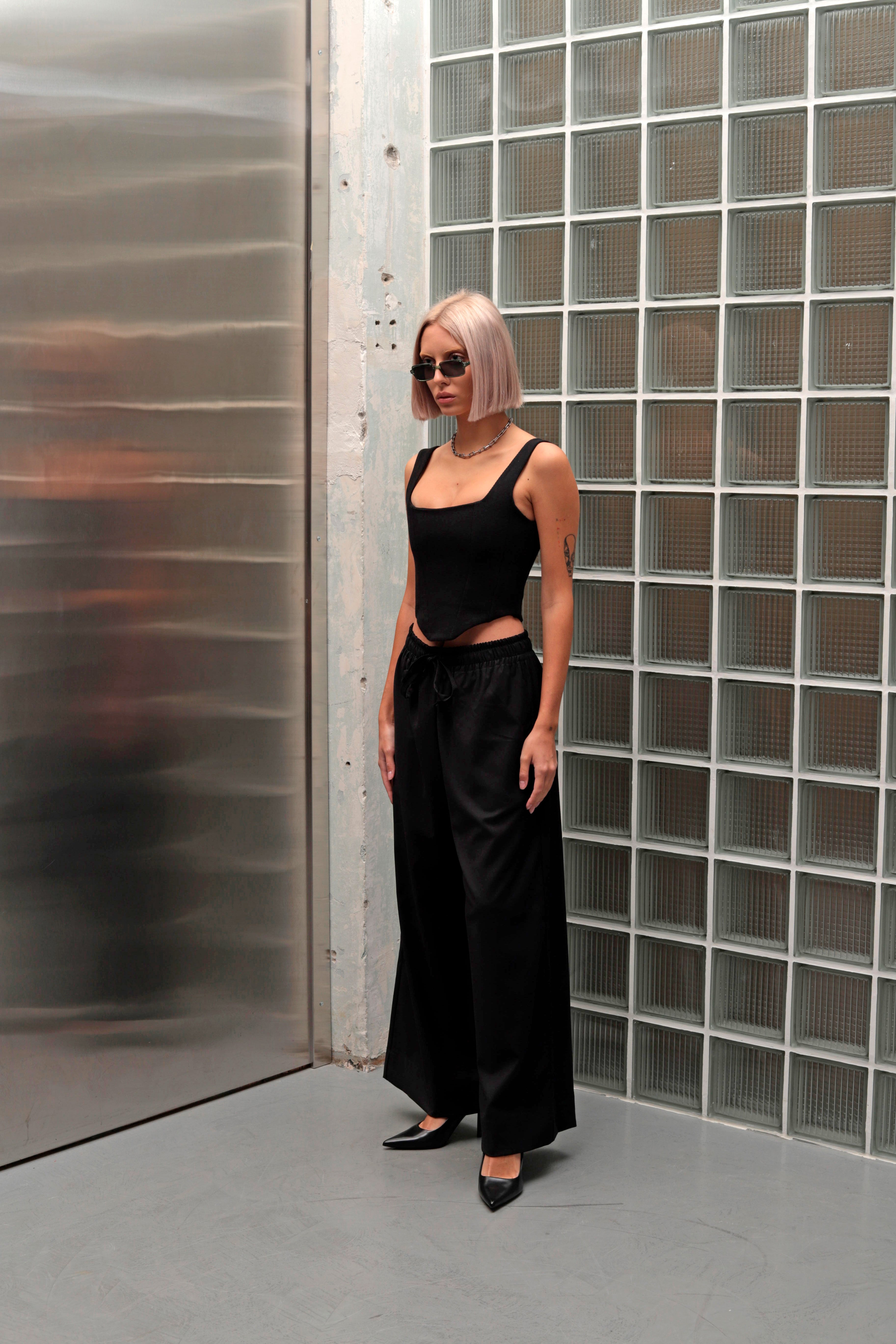 Model standing with back to the camera, wearing wide-leg pants made from suiting fabric, showcasing the elegant and comfortable fit of these versatile pant