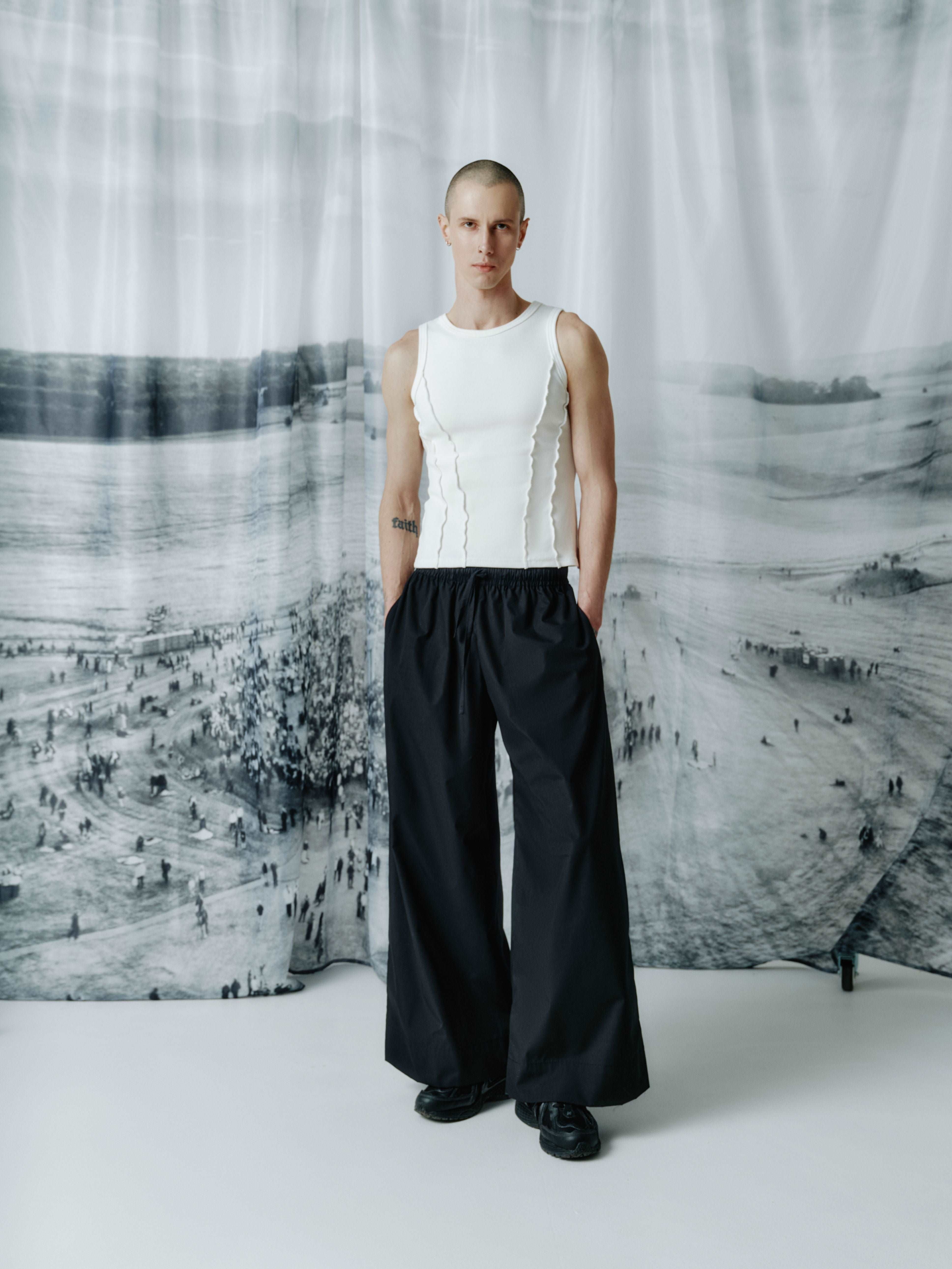 Model wearing full-length black cotton wide-leg pants with an elastic waistband, offering a modern and comfortable fit for a versatile look