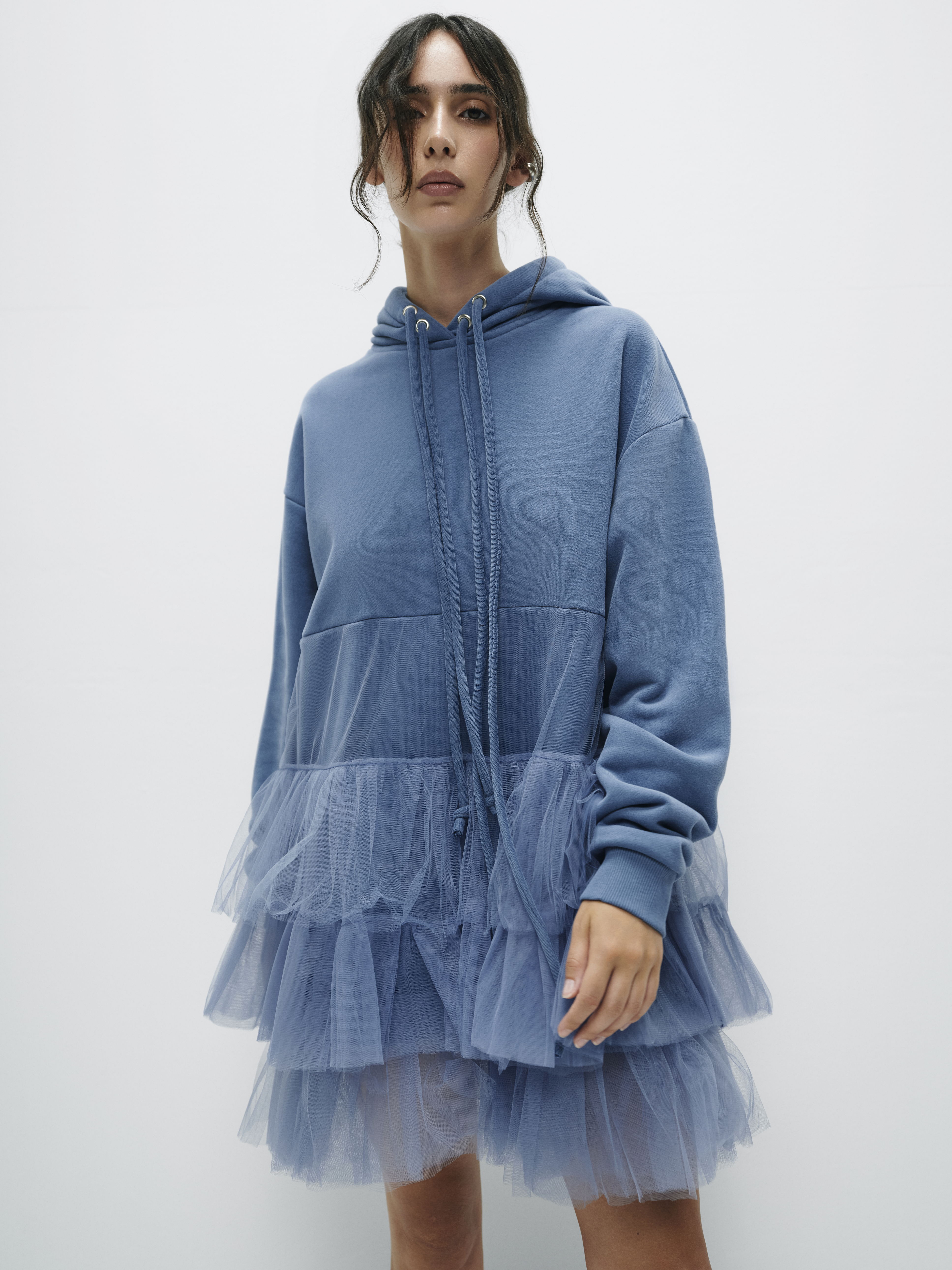 Knee-length view of hoodie dress with layered tulle from the waist, creating a voluminous, contemporary silhouette