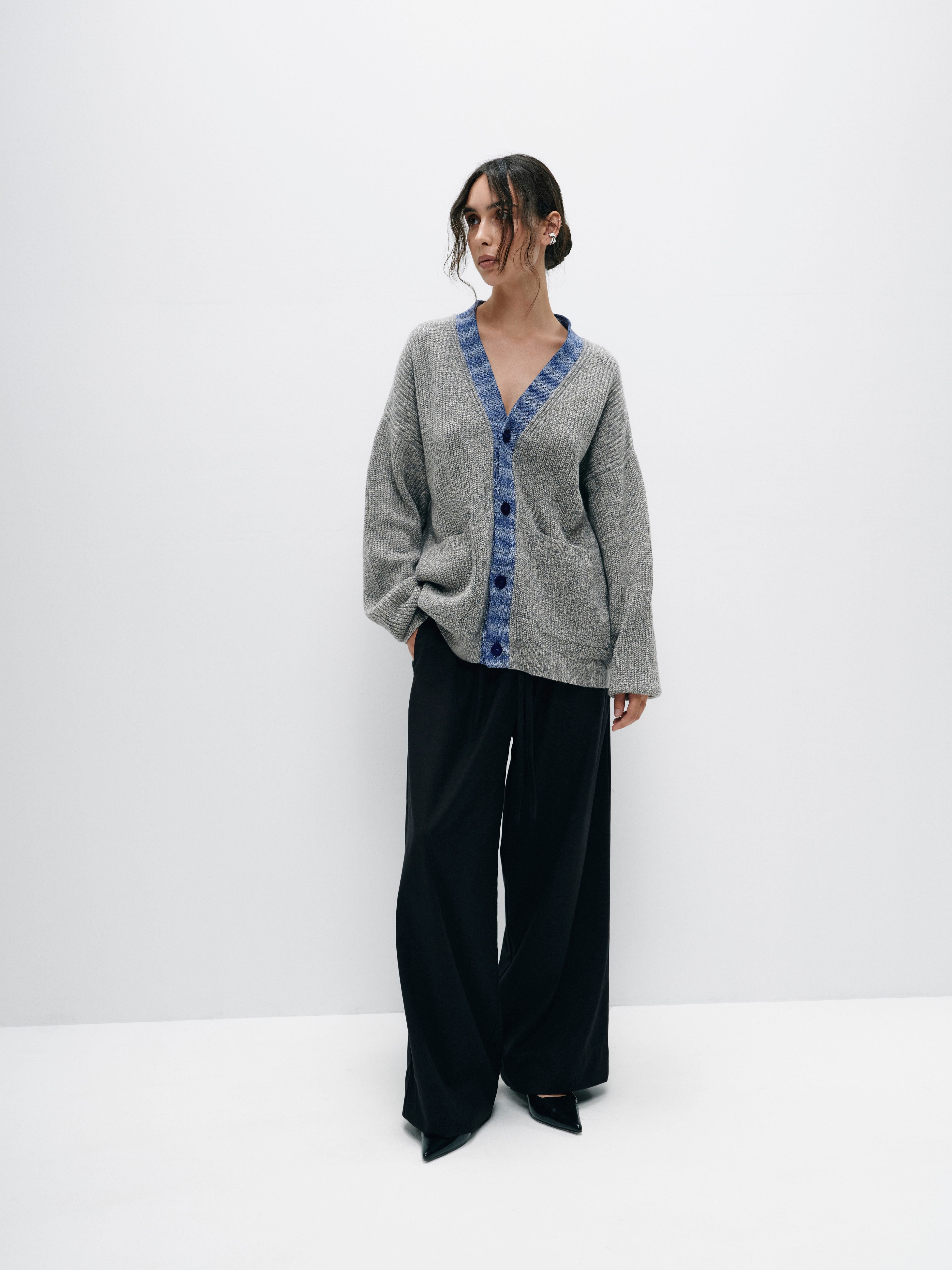 Close-up of the contrasting light blue cuffs on the gray merino wool cardigan, highlighting the subtle pop of color
