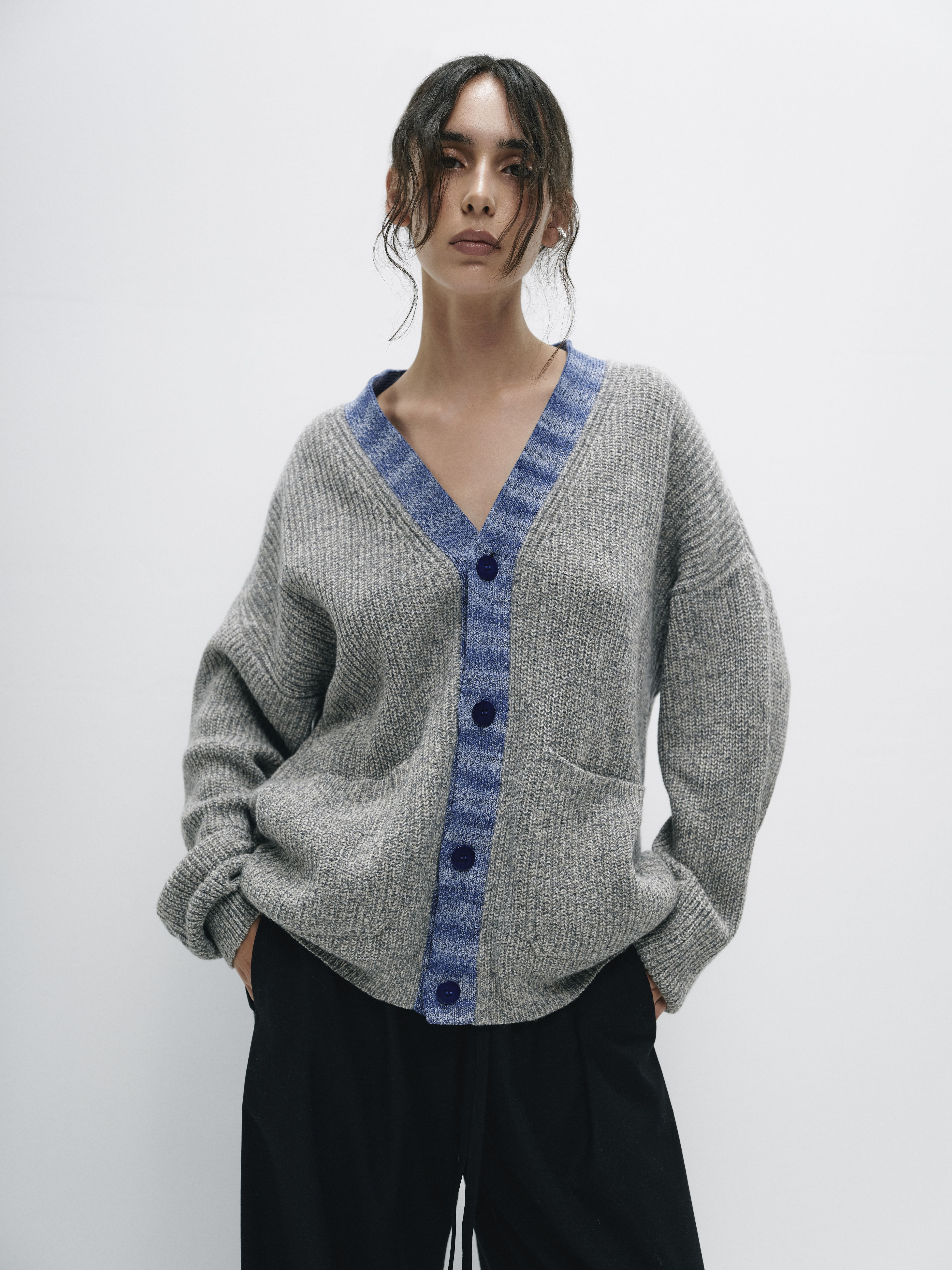 Back view of the model in the gray merino wool cardigan, emphasizing the soft, comfortable fit and the refined texture