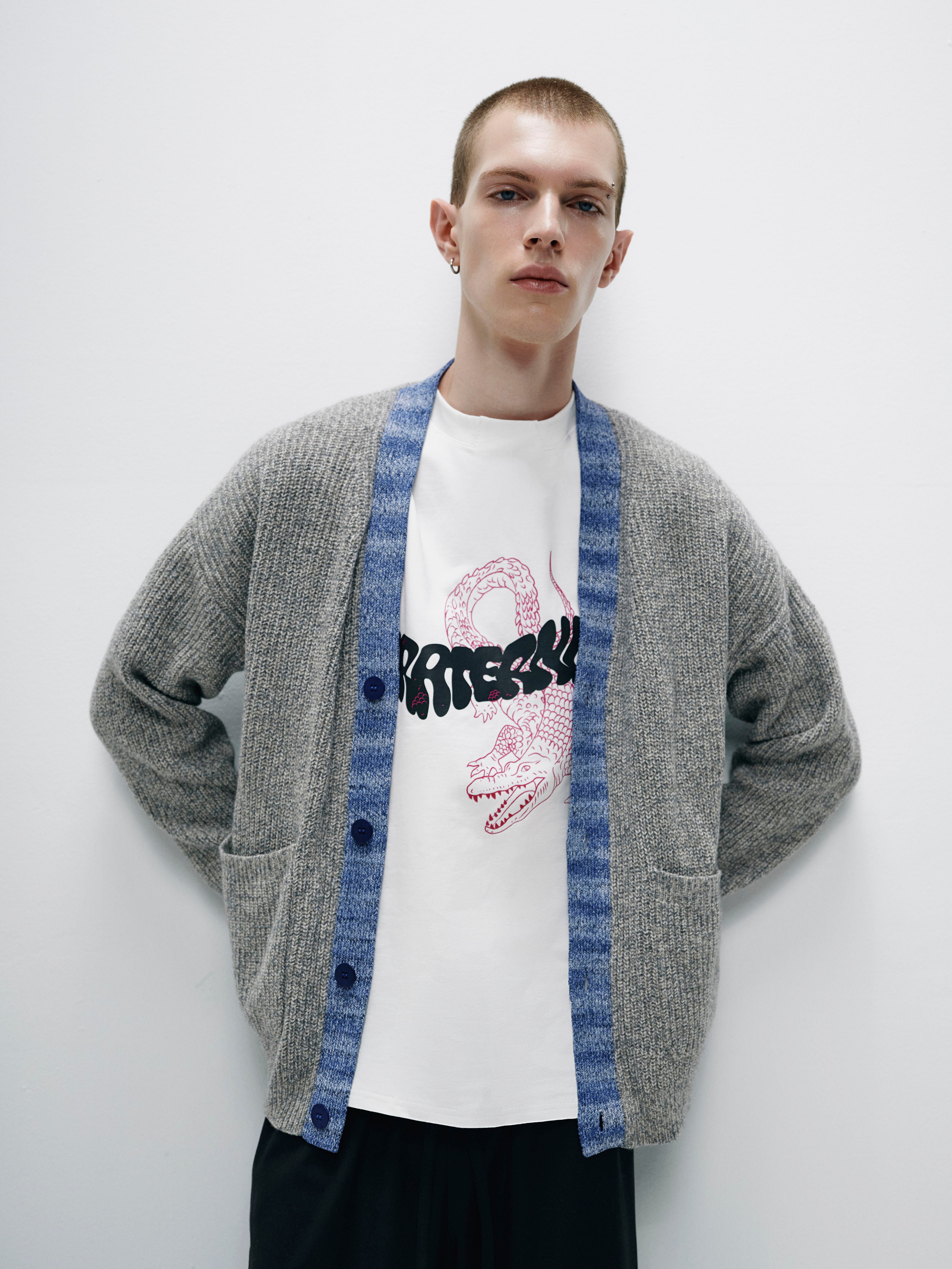 Side view of the model in the gray merino wool cardigan, accentuating the textured mélange finish and flattering silhouette