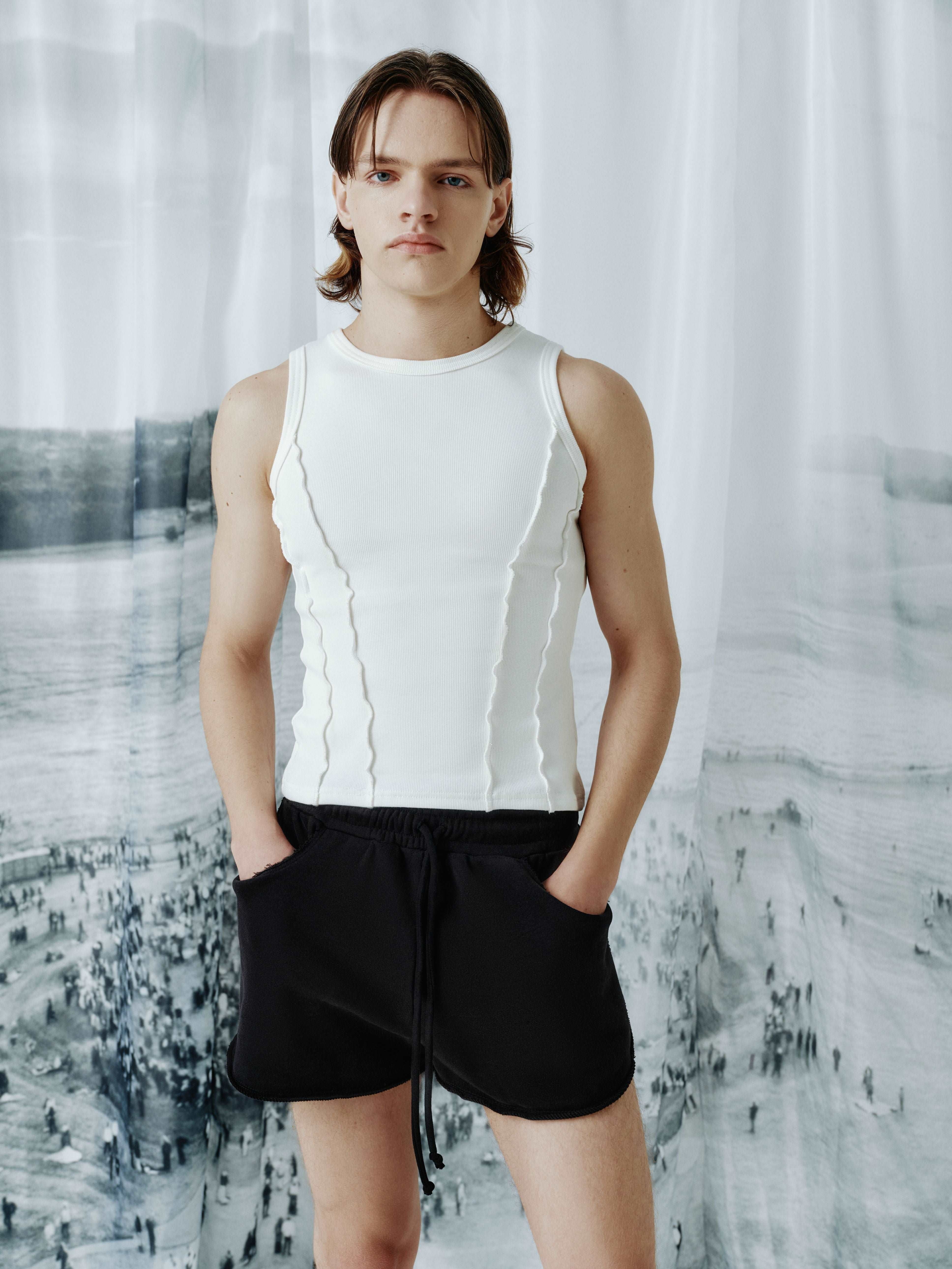Male model wearing a ribbed tank top with corset-inspired front seams, showcasing the unique streetwear style and modern fit