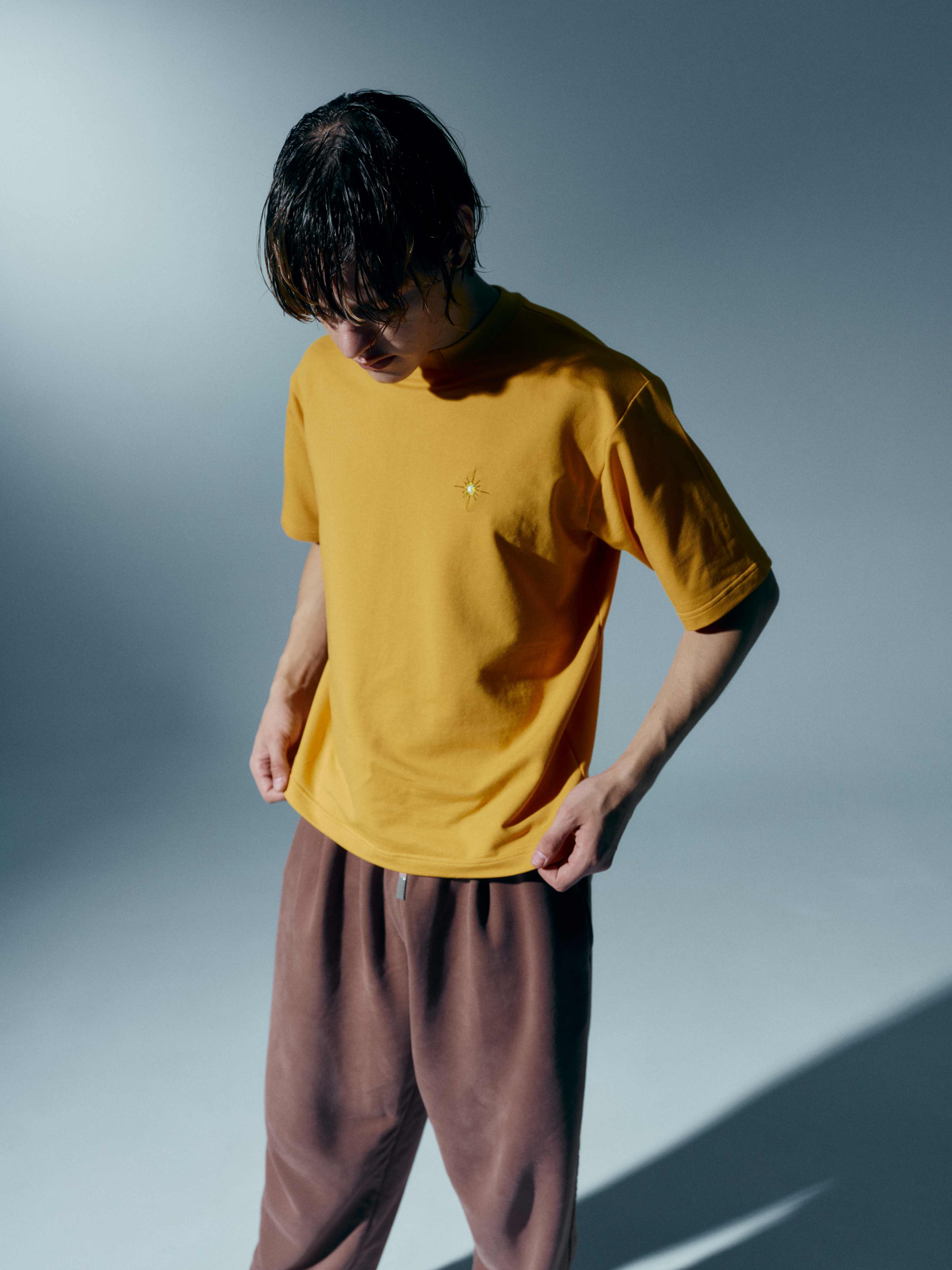 Model standing in a mustard yellow unisex cotton t-shirt with a stand-up collar, showcasing the perfect blend of elegance and comfort