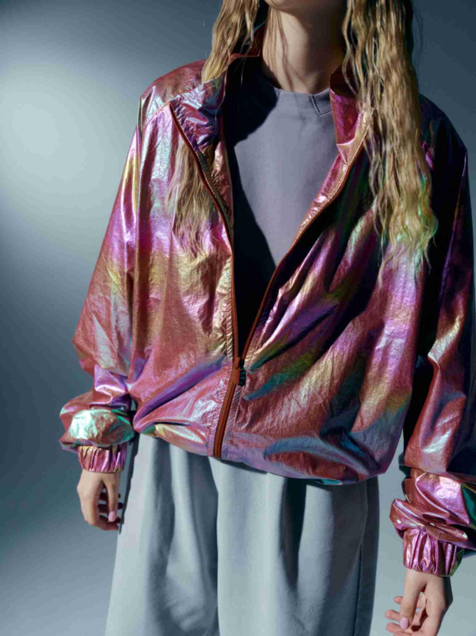 Model standing outdoors in the holographic windbreaker, blending urban street style with bold, futuristic aesthetics